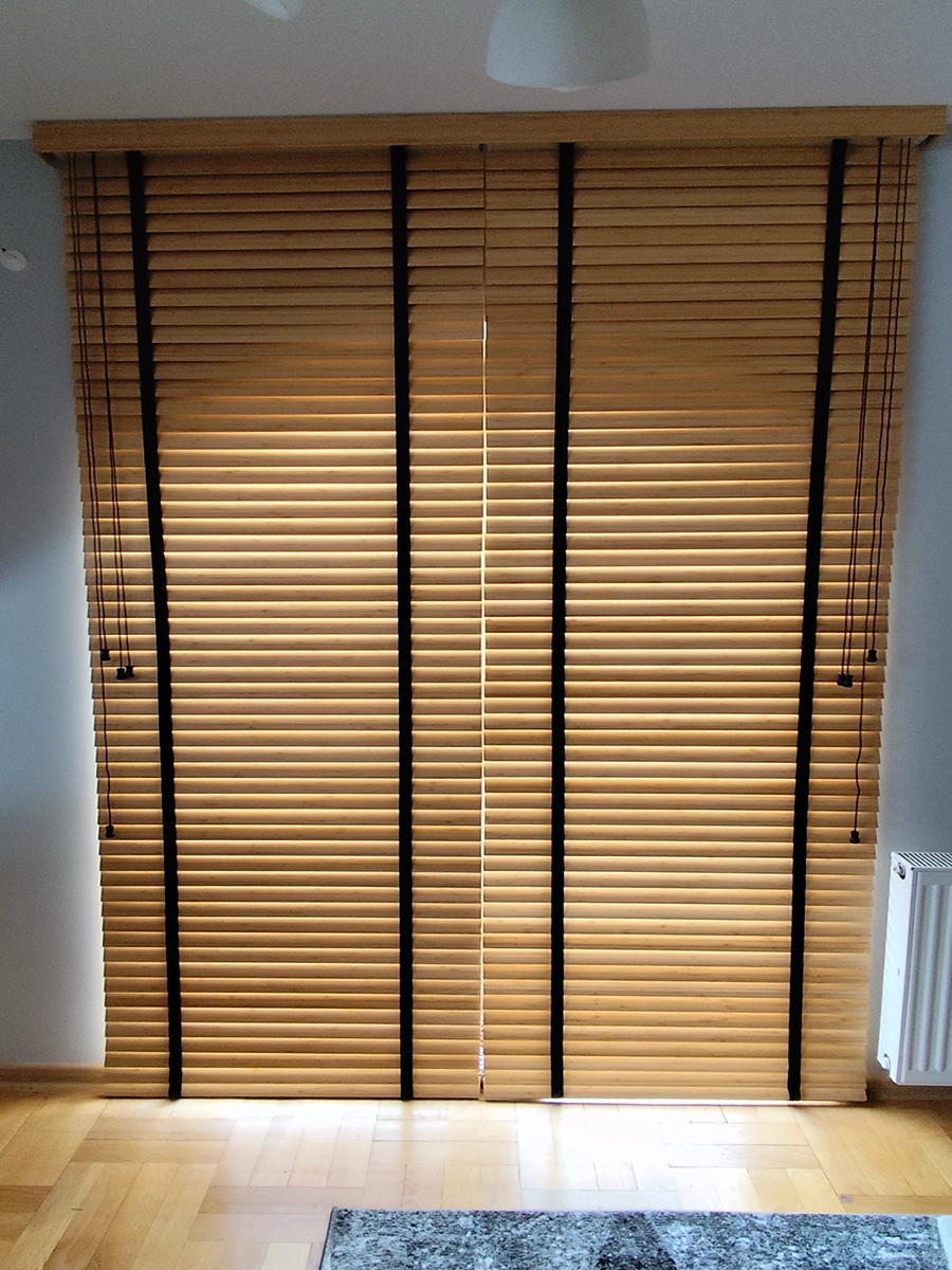 Żaluzje drewniane 50 mm w naturalnym kolorze na dużym oknie w salonie