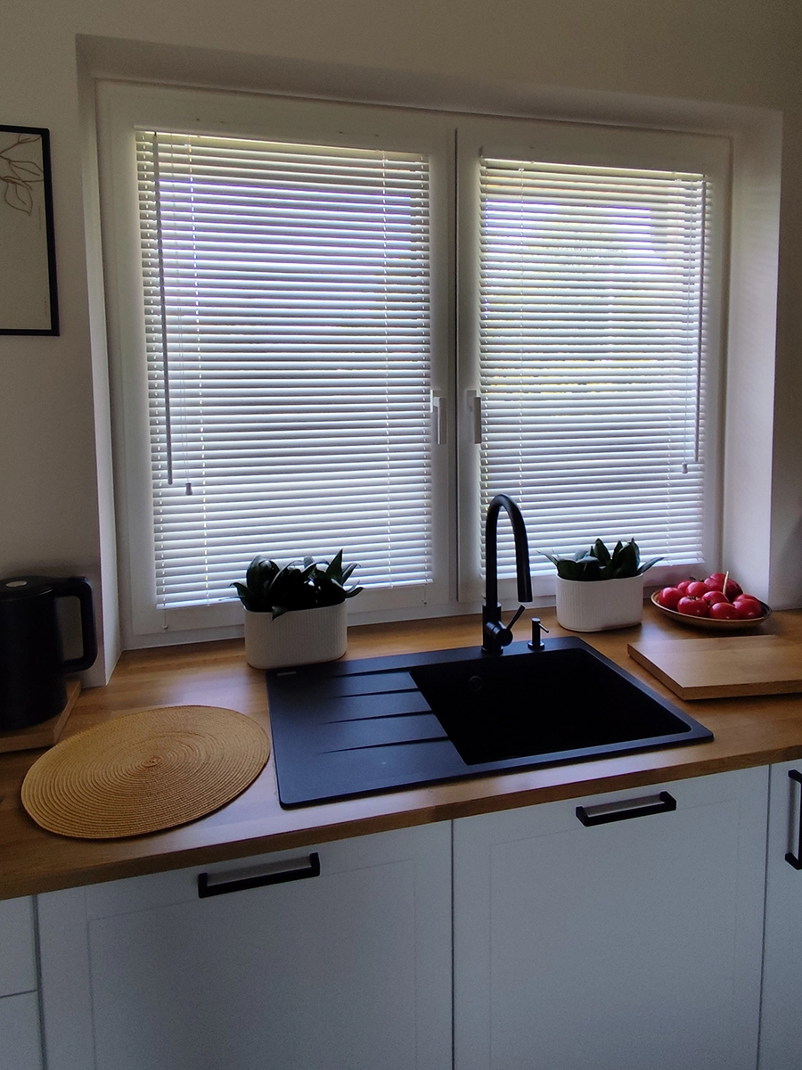 Białe żaluzje drewniane 25 mm w kuchni nad zlewem